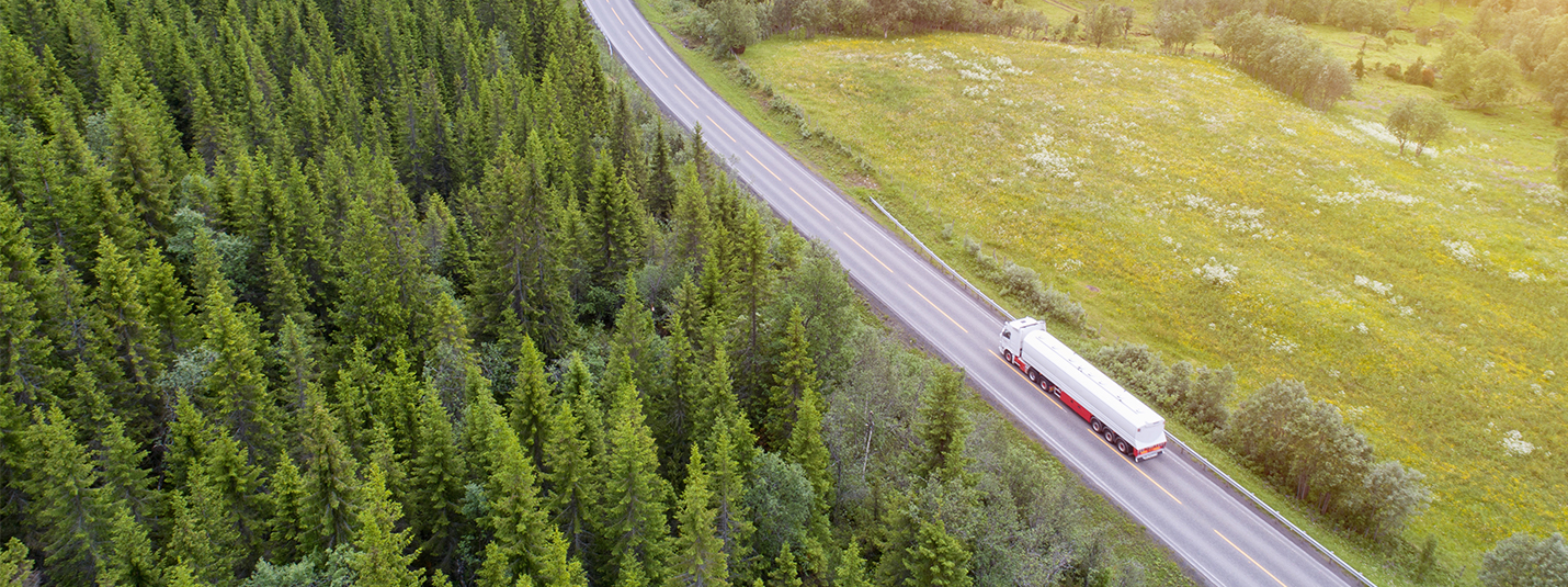 Semi truck driving on two lane highway through forest. Q-Free HI-TRAC UTC-P | traffic counter and classification system